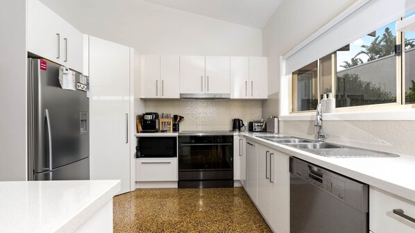 Enjoy cooking in this well-equipped kitchen with a refrigerator, oven, dishwasher, and coffee maker.