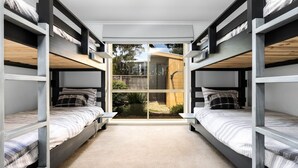 A dormitory room with bunk beds, a large window, and a view of the outdoors.