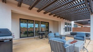 Un patio al aire libre con una parrilla, zona de estar y una pérgola.