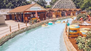 Un parque acuático con un tobogán de agua, una montaña rusa y un edificio que dice 'LOCKERS'.
