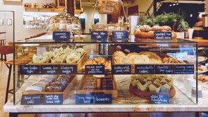 Una vitrina de panadería con diversas opciones horneadas como muffins, galletas y pasteles.