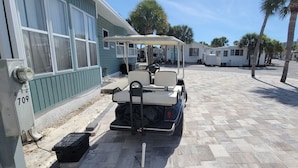 Un golf cart parcheggiato in un'area di parcheggio, sullo sfondo un edificio con la scritta '709'.
