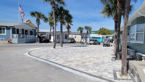 Un hotel sulla spiaggia con una bandiera, palme e un'area parcheggio.