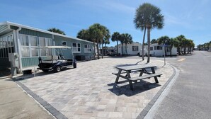 Una strada con un tavolo da picnic al centro, circondata da palme e camper.
