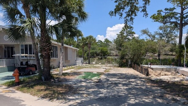 A residential area with a house, palm trees, a fire hydrant, and a fenced yard. - Venture Out 484, Large RV Lot (Panama City)