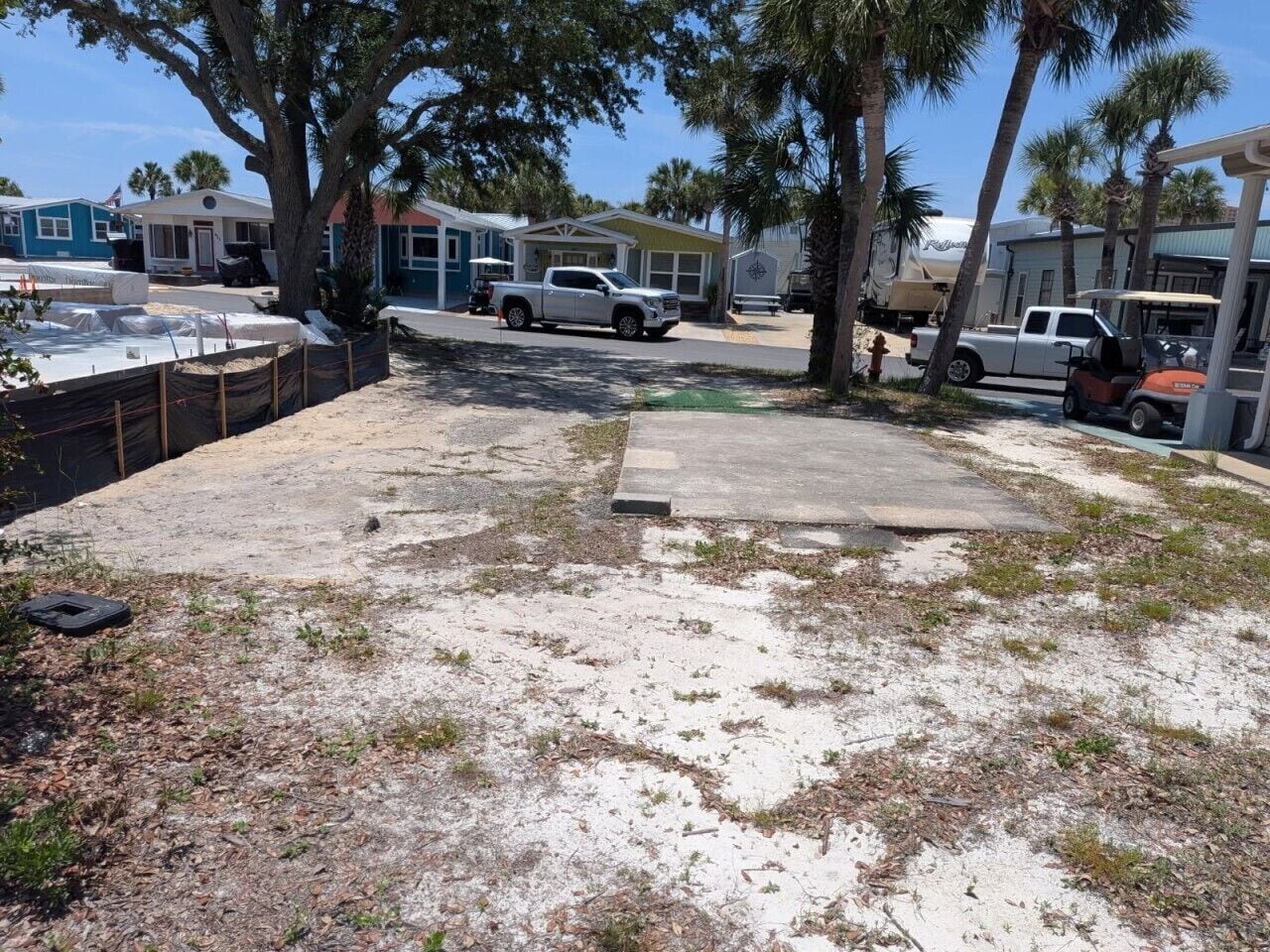 A backyard with a concrete patio, a white pickup truck, and a boat trailer.
