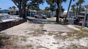 A backyard with a concrete patio, a white pickup truck, and a boat trailer. - Venture Out 484, Large RV Lot (Panama City)