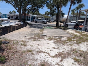 A backyard with a concrete patio, a white pickup truck, and a boat trailer.