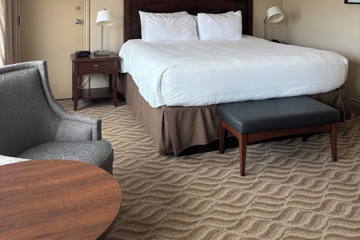 A hotel room with a large bed, bedside tables, a chair, and a round table.