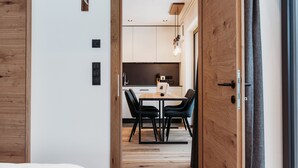 A modern kitchen with wooden cabinets, a dining table with chairs, and pendant lighting. - Modern-traditional apartment with a great view (Albeins)