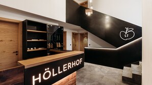 A reception desk with a sign reading "HÖLLERHOF" in a modern interior with a staircase and wooden elements. - Modern-traditional apartment with a great view (Albeins)