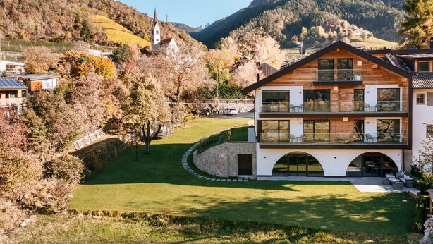 A modern two-story house with a stone foundation, large windows, and a balcony. - Modern-traditional apartment with a great view (Albeins)