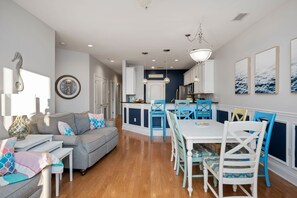 Une cuisine moderne avec des meubles blancs, un îlot central et des chaises bleues.