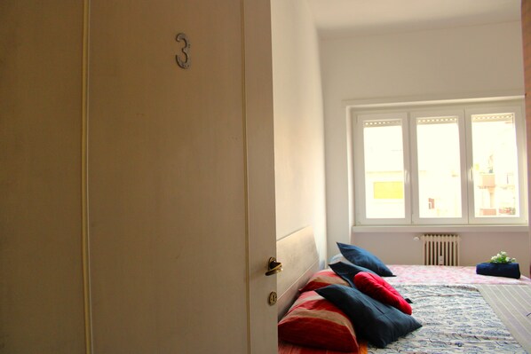 A bedroom with a bed, a radiator, and a window.