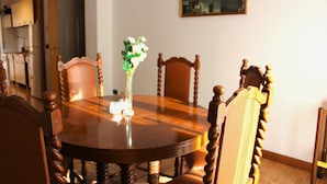 Une table à manger avec des chaises, un vase rempli de fleurs et un tableau accroché au mur.