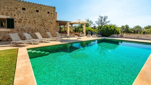 A swimming pool with lounge chairs and a stone building in the background. - Son Viverassa, Finca 5StarsHome Mallorca (Son Servera)