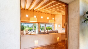 A modern kitchen with wooden beams, large windows, and a view of the outdoors. - Son Viverassa, Finca 5StarsHome Mallorca (Son Servera)