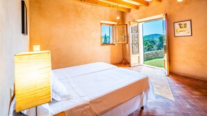 A bedroom with a bed, a bedside lamp, a window, and a door leading to a balcony with a view of the outdoors. - Son Viverassa, Finca 5StarsHome Mallorca (Son Servera)