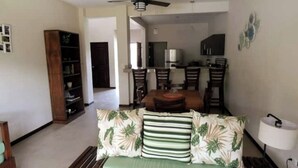 A living room with a sofa, a dining table with chairs, a kitchen area, and a ceiling fan. - Private house with pool, near Tamarindo. (Provincia de Guanacaste)