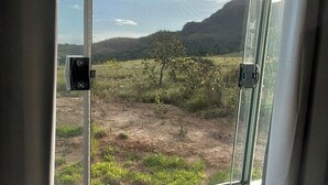 Een keuken met een granieten aanrecht, een roestvrijstalen spoelbak en een raam met uitzicht op een landschap met bergen en groen.