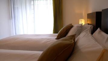 Una habitación de hotel con una cama grande, un cabecero con una lámpara y cortinas translúcidas.