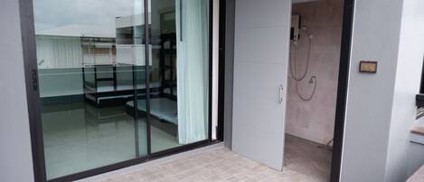 A modern bathroom with a glass shower enclosure, a white door, and a tiled floor.