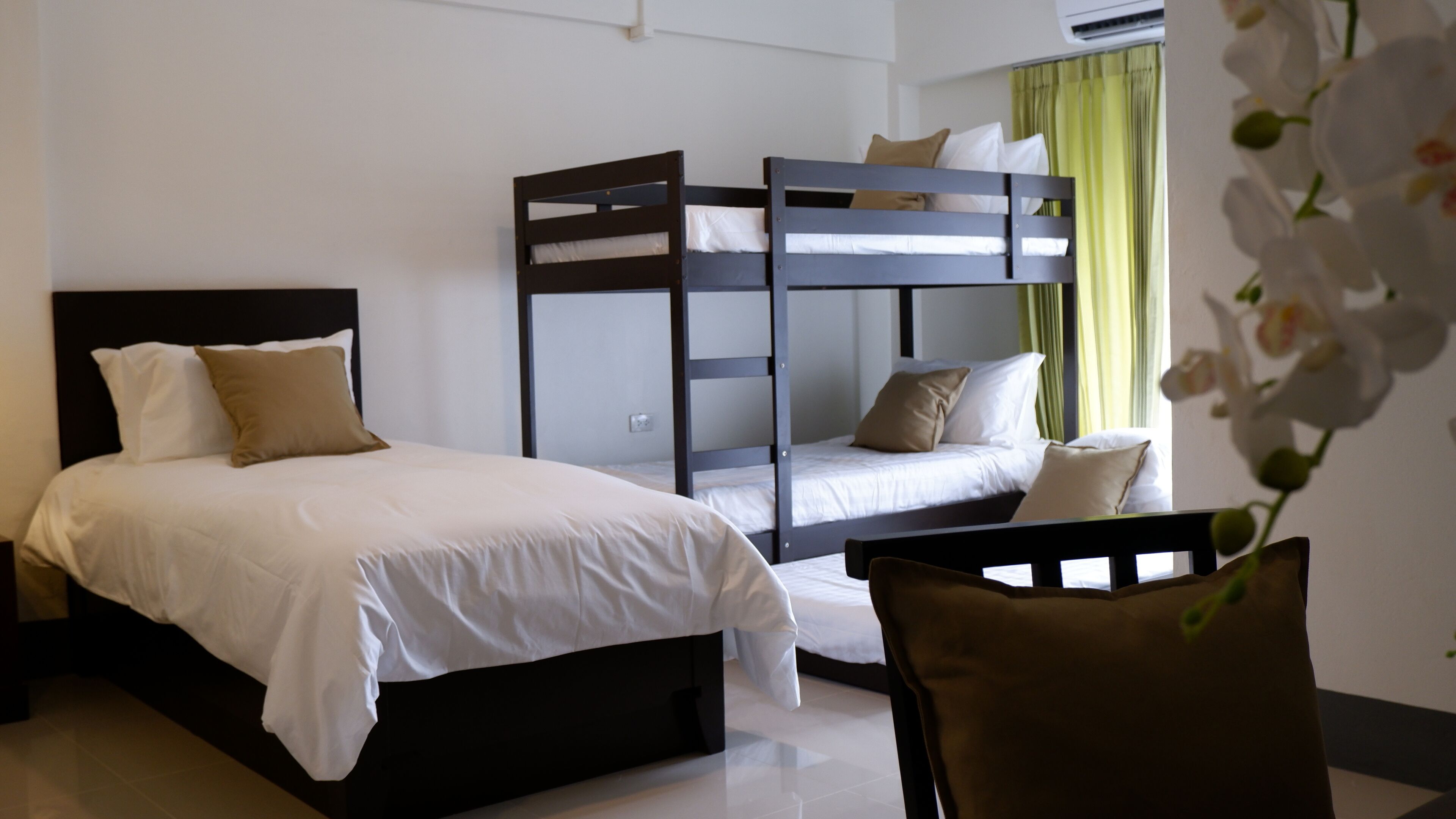 A hotel room with a bunk bed, a single bed, and a chair.
