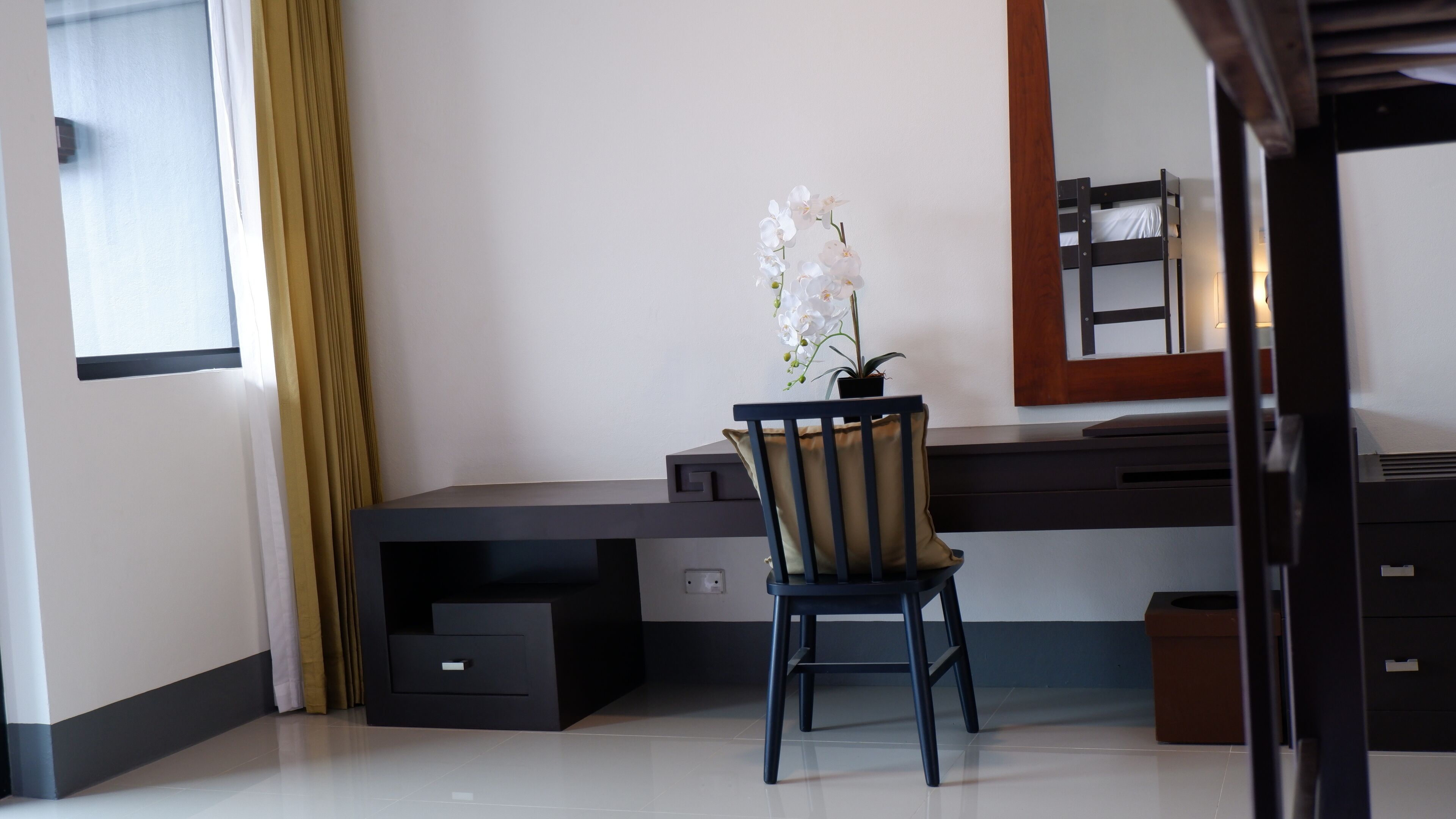 A modern office space with a desk, chair, and a potted orchid.