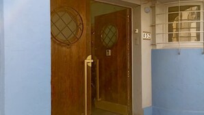 Une entrée d’immeuble avec une porte en bois et une fenêtre à carreaux.