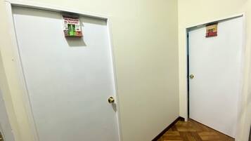 Un pasillo con dos puertas blancas, cada una con una pequeña señal encima. El piso es de madera.