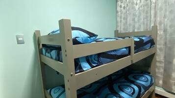 Una cama litera con ropa de cama estampada en azul en una habitación con paredes azul claro y suelo de madera.
