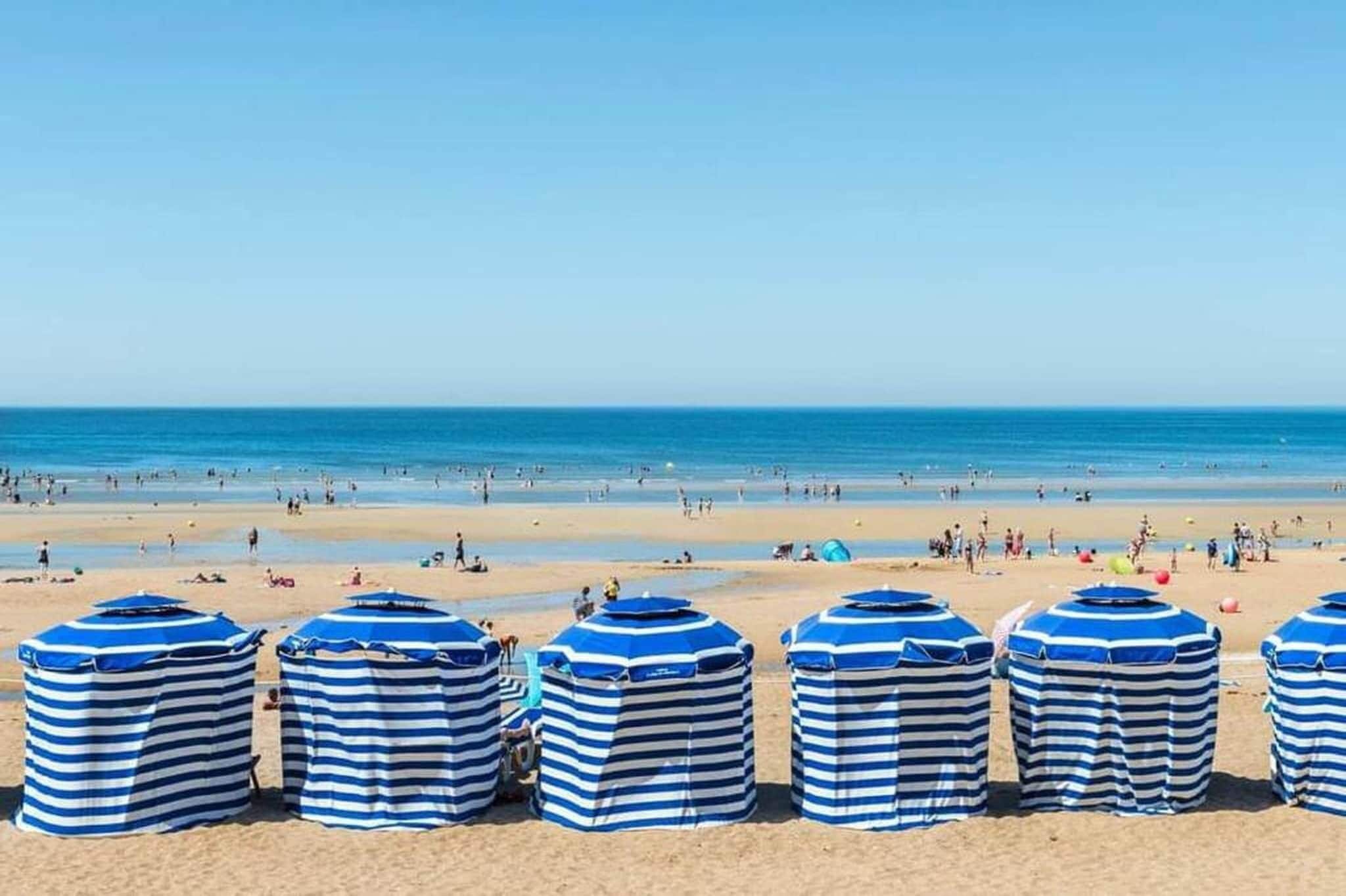 A beach with striped umbrellas and people in the distance.