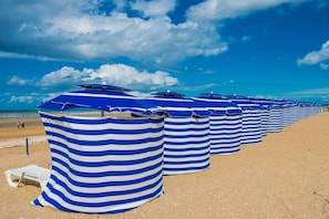 A beach with rows of striped beach umbrellas. - Apartment in Cabourg near Beaches (Cabourg)
