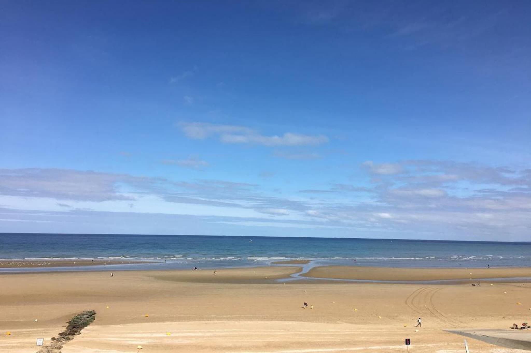 A beach with a clear sky, sandy shore, and a calm sea.