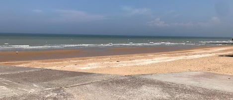 Una playa con un paseo marítimo de hormigón que llega hasta la orilla.