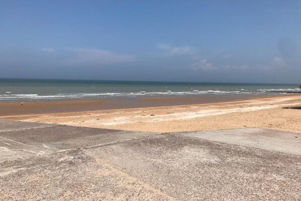 A beach with a concrete walkway leading to the shore.