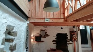Interior de madera con lámpara colgante, pared de piedra y chimenea.
