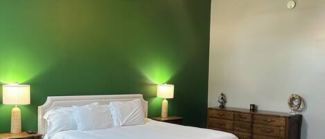 Une chambre à coucher comprenant un lit, deux lampes de chevet, un ventilateur de plafond, une commode et une table de chevet.