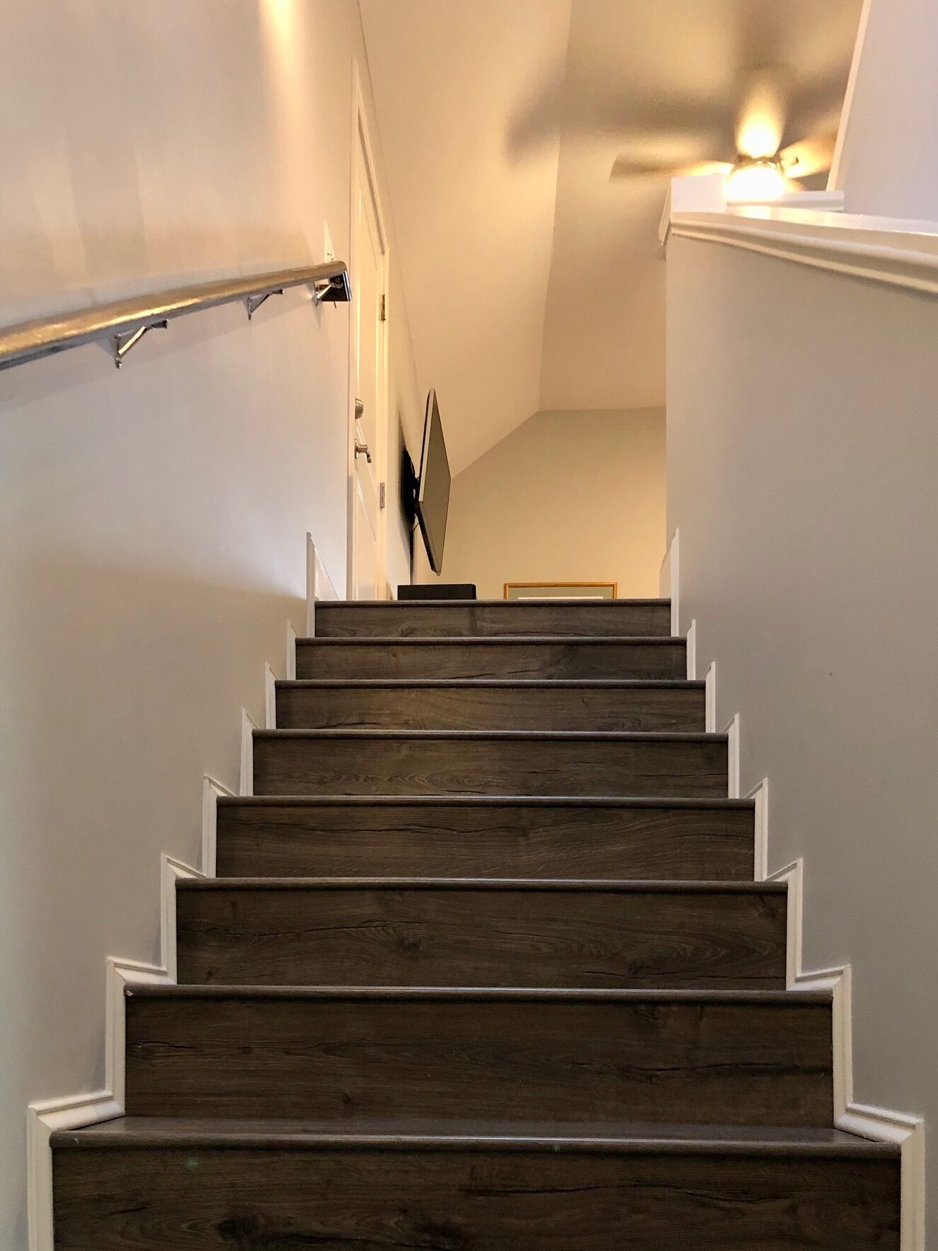 Eine Holztreppe mit weißen Geländern und einem Deckenventilator.