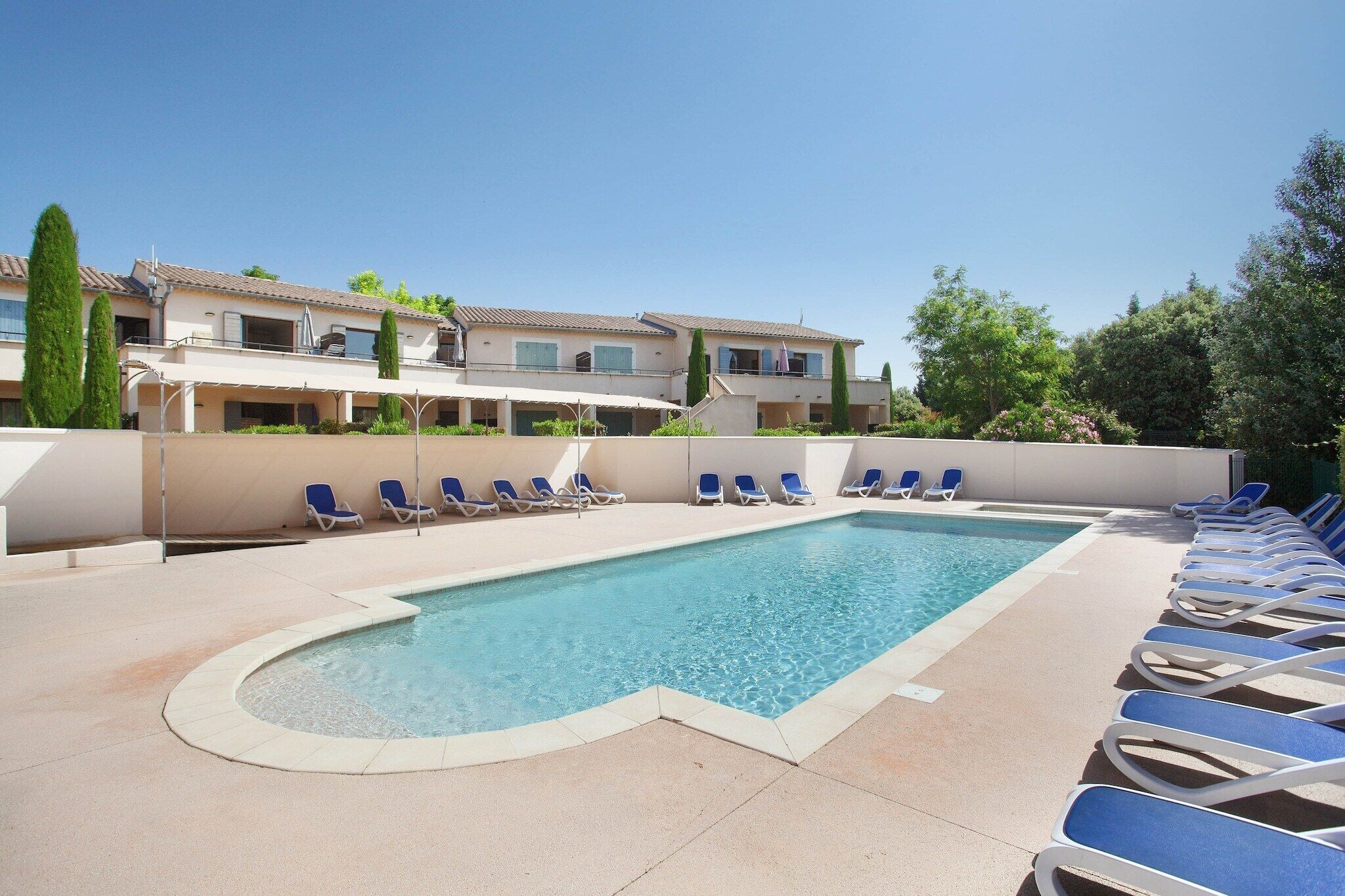A swimming pool with lounge chairs and a building in the background.