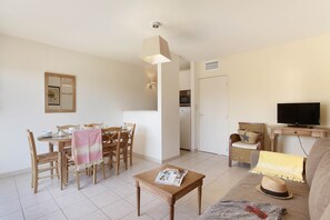 A living room with a dining area, a television, and a kitchen in the background.