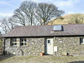 A stone cottage with a sloped roof, a door, and a window.