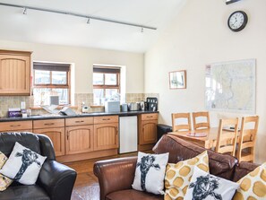 A kitchen with wooden cabinets, a dining table with chairs, and a clock on the wall.
