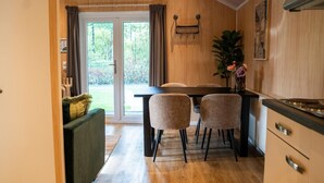 Et moderne køkken med træskabe, et spiseområde med bord og stole, og en skydedør til en have.