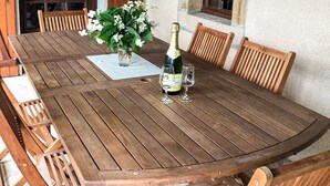 A wooden dining table with a bottle of champagne and two glasses, surrounded by wooden chairs. - Delightful holiday home with a large private swimming pool, perfect for families (Cérilly)