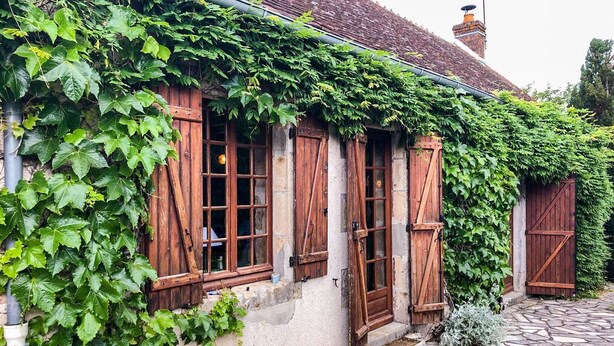A rustic building with ivy-covered walls, wooden shutters, and a stone-paved entrance. - Delightful holiday home with a large private swimming pool, perfect for families (Cérilly)