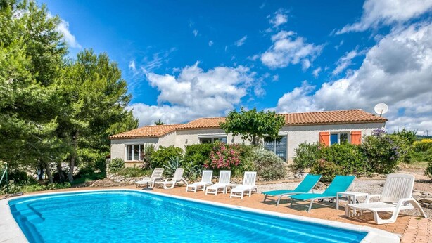 A swimming pool with lounge chairs, a house with a tiled roof, and surrounding greenery. - Spacious villa with pool in Le Canet (Soleil d'Oc (Pouzols Minervois))