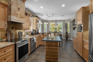 A modern kitchen with granite countertops, stainless steel appliances, wooden cabinets, and a central island.