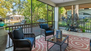 A covered outdoor patio with wicker furniture, a ceiling fan, and a view of a house and RV in the background.