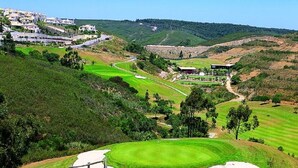 A golf course with a clubhouse, sand bunkers, and a residential area in the background. - Stunning views, private position - 5 mins to beach!  Heated pool option & Aircon (Budens)